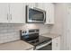 Close-up of a kitchen featuring stainless steel appliances, white subway tile backsplash, gray countertops, and white cabinets at 17758 W Getty Dr, Goodyear, AZ 85338