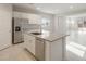 Bright, open kitchen features stainless steel appliances, white cabinetry, a center island with a sink, and tile flooring at 17758 W Getty Dr, Goodyear, AZ 85338