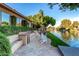 Waterfront backyard features a BBQ, sink, and steps down to a lake with lush landscaping and lounge seating at 1833 W Mead Pl, Chandler, AZ 85248