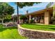 Inviting backyard features a covered patio with lounge chairs, lush lawn, and stone retaining wall for added privacy at 1833 W Mead Pl, Chandler, AZ 85248