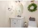 Well-lit bathroom with a white vanity cabinet, a round mirror, and a decorative wreath at 18934 E Happy Rd, Queen Creek, AZ 85142