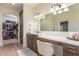 Well-lit bathroom featuring a vanity with seating, dual sinks, and access to a walk-in closet at 18934 E Happy Rd, Queen Creek, AZ 85142