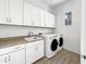 A well-organized laundry room featuring white cabinets, a sink, and a modern washer and dryer at 20075 E Kestrel St, Queen Creek, AZ 85142