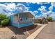 Light blue home featuring a covered porch with white railing and desert-style landscaping in a sunny neighborhood at 201 S Greenfield Rd # 144, Mesa, AZ 85206