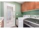 Modern laundry room with white cabinets, green wall, a utility sink, and Maytag washer and dryer at 2131 E New Bedford Dr, Gilbert, AZ 85234