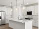 A modern kitchen featuring white cabinets, stainless steel appliances, and a large island with pendant lighting at 24493 W Grenadine Rd, Buckeye, AZ 85326