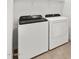 Modern laundry room with new white front load washing machine and dryer and overhead storage shelving at 24493 W Grenadine Rd, Buckeye, AZ 85326