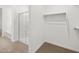 Bright walk-in closet with a glass enclosed shower, built in shelving, neutral tones and plush carpet at 24493 W Grenadine Rd, Buckeye, AZ 85326