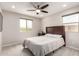Minimalist bedroom with neutral tones, a simple bed, two windows, and a ceiling fan, creating a serene space at 2605 W Golden Puma Trl, Phoenix, AZ 85085