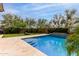 Sparkling pool with a basketball hoop, turf, travertine decking, and green landscaping for a backyard oasis at 2605 W Golden Puma Trl, Phoenix, AZ 85085