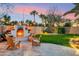Beautiful backyard featuring a stone fireplace, chairs, and well-manicured lawn and landscaping at 3921 W Sheffield Ave, Chandler, AZ 85226