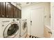 Functional laundry room equipped with a washer, dryer, and ample dark wood cabinet storage at 3921 W Sheffield Ave, Chandler, AZ 85226