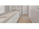 Bathroom boasting dual sinks with a stone countertop, white cabinetry, and plank tile flooring at 4119 S 176Th Dr, Goodyear, AZ 85338