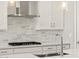 Modern kitchen with stainless steel range hood, mosaic backsplash, and chrome faucet at 4813 N 177Th Ln, Goodyear, AZ 85395