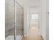 Modern tiled shower with glass door, seamlessly connected to a hallway with wood-look floors at 4813 N 177Th Ln, Goodyear, AZ 85395
