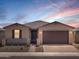 A single-story home during twilight with desert landscaping, a two-car garage, and charming stone accents at 4819 N 177Th Ln, Goodyear, AZ 85395