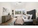 Sunlit bedroom with a tufted headboard, stylish dresser, and a cozy sitting area by the window at 665 W Beechnut Dr, Chandler, AZ 85248