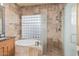 Luxurious bathroom with stone tile, glass shower, and soaking tub with glass block window for natural light at 7538 E Tuckey Ln, Scottsdale, AZ 85250