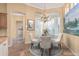 Bright breakfast nook features elegant chandelier, round glass table, and white plantation shutters at 7538 E Tuckey Ln, Scottsdale, AZ 85250