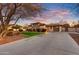 Well-maintained home with a long driveway, lush landscaping, and stone accents, all captured under a stunning sunset sky at 911 E Desert Inn Dr, Chandler, AZ 85249