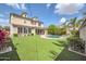 Expansive backyard featuring a pool, well-maintained lawn, and a charming two-story home in the background at 10749 E Nido Ave, Mesa, AZ 85209