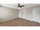 Bedroom with wood flooring, ceiling fan, and three white doors at 129 S 198Th Dr, Buckeye, AZ 85326
