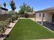 Manicured backyard featuring artificial turf, desert landscaping, and a covered patio at 6049 E Glencove St, Mesa, AZ 85205