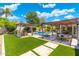 Beautiful backyard featuring pool, artificial grass, multiple seating areas, and lush landscaping at 7722 E Hartford Dr, Scottsdale, AZ 85255
