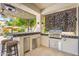 Outdoor kitchen with stainless steel grill, beverage cooler, patterned backsplash, and decorative shade structure at 7722 E Hartford Dr, Scottsdale, AZ 85255