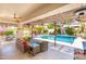 Inviting outdoor living space with wicker seating, a pool view, and a decorative pergola at 7722 E Hartford Dr, Scottsdale, AZ 85255