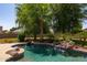 Relaxing backyard pool with waterfall, set amidst lush landscaping and mature trees, creating a private oasis at 19515 E Via Del Palo --, Queen Creek, AZ 85142