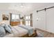 Bright bedroom with wood floors, rustic dresser, sliding barn door and natural light at 20815 N 119 Th Ave, Sun City, AZ 85373