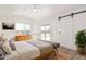 Bright bedroom with wood floors, rustic dresser, sliding barn door and natural light at 20815 N 119 Th Ave, Sun City, AZ 85373