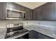 Close-up of updated kitchen with stainless steel microwave, oven, and dark wood cabinets with granite counter tops at 4906 E Evergreen St, Mesa, AZ 85205