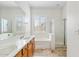 Bright bathroom with double sinks, a shower, a soaking tub, and shuttered window at 10603 E Firewheel Dr, Scottsdale, AZ 85255