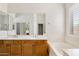 Bright bathroom with double sinks, large mirror, soaking tub, and ample storage at 10603 E Firewheel Dr, Scottsdale, AZ 85255
