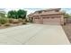 Large driveway leading to a three-car garage with desert landscaping and lush trees at 10653 E Lindner Cir, Mesa, AZ 85209