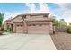 Three-car garage of a home with a tile roof and desert landscaping at 10653 E Lindner Cir, Mesa, AZ 85209