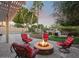 Inviting backyard featuring a stone fire pit with red chairs, a pergola with string lights, and lake views at 1457 W Bahia Ct, Gilbert, AZ 85233