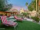 Landscaped backyard with lounge chairs, covered patio, and mature palm trees at 1457 W Bahia Ct, Gilbert, AZ 85233