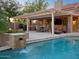 Stunning backyard with pool, waterfall feature, and outdoor kitchen with covered patio at 1457 W Bahia Ct, Gilbert, AZ 85233