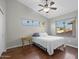 Bedroom featuring hardwood floors, ceiling fan, and bright windows showcasing palm trees at 1457 W Bahia Ct, Gilbert, AZ 85233