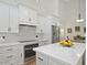 Bright kitchen features stainless steel appliances, white cabinets, stone backsplash and an island with a quartz countertop at 1457 W Bahia Ct, Gilbert, AZ 85233