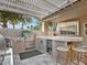Outdoor kitchen features a built-in grill, mini-fridge, and bar seating under a pergola at 1457 W Bahia Ct, Gilbert, AZ 85233