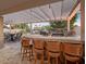 Covered outdoor kitchen with built-in grill, bar seating, and patio furniture at 1457 W Bahia Ct, Gilbert, AZ 85233
