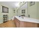 Well-lit bathroom featuring a double sink vanity with framed mirror and decorative wall art at 14575 W Mountain View Blvd # 11315, Surprise, AZ 85374