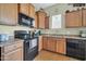 Efficient kitchen area with oak cabinets, stainless sink, and modern black appliances at 14575 W Mountain View Blvd # 11315, Surprise, AZ 85374
