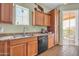 Galley kitchen featuring oak cabinets, stainless steel sink, and modern appliances at 14575 W Mountain View Blvd # 11315, Surprise, AZ 85374