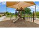 Community playground with a shade sail, and a variety of play equipment, surrounded by lush landscaping at 15138 W Campbell Ave, Goodyear, AZ 85395