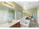 Large bathroom featuring dual sinks, a soaking tub, and separate glass door shower at 16158 W Christy Dr, Surprise, AZ 85379